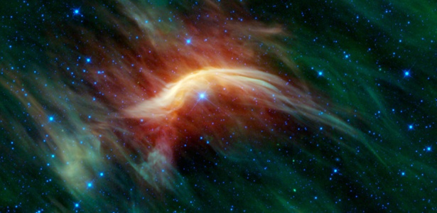 Nesta imagem, a luz infravermelha faz a estrela Zeta Ophiuchi aparecer como o ponto azul dentro da onda de choque de poeira e gás, em amarelo - NASA/JPL-Caltech/UCLA
